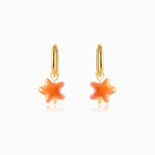 Gold hoop earrings with orange ceramic starfish on a white background