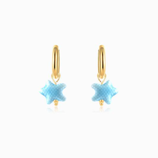 Gold hoop earrings with blue ceramic starfish on a white background