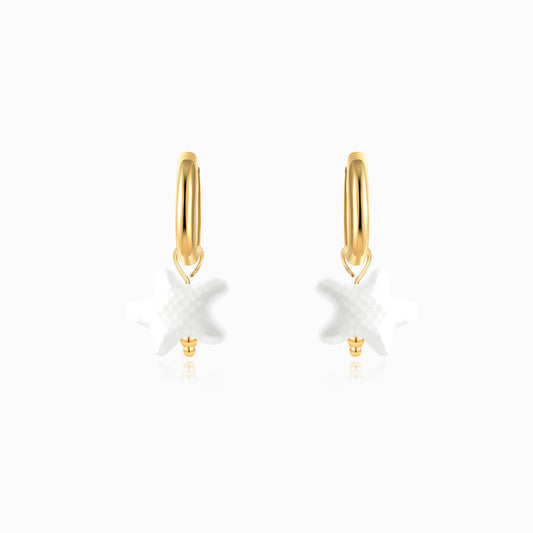 Gold hoop earrings with white starfish charms on a white background
